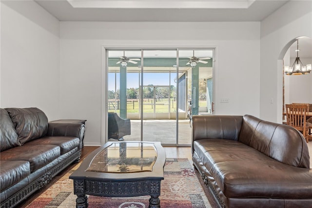 living room with arched walkways, wood finished floors, and ceiling fan with notable chandelier