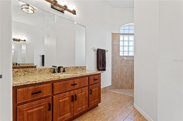 full bath with vanity, baseboards, tile patterned flooring, and walk in shower