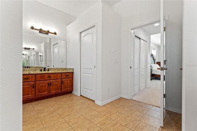 ensuite bathroom with tile patterned floors, baseboards, ensuite bathroom, and vanity