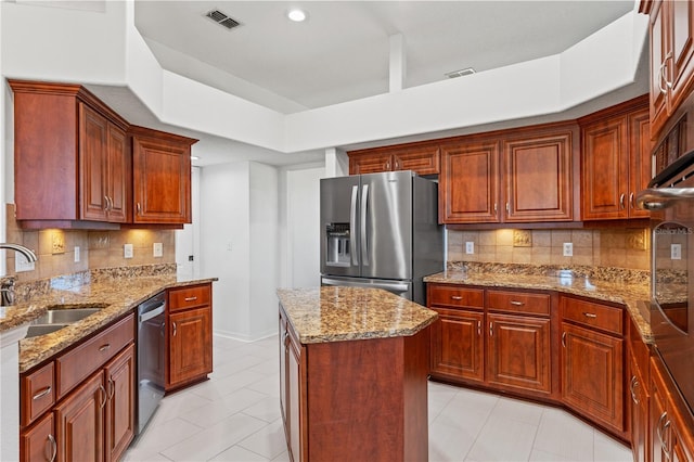 kitchen featuring light stone counters, visible vents, a tray ceiling, a sink, and appliances with stainless steel finishes