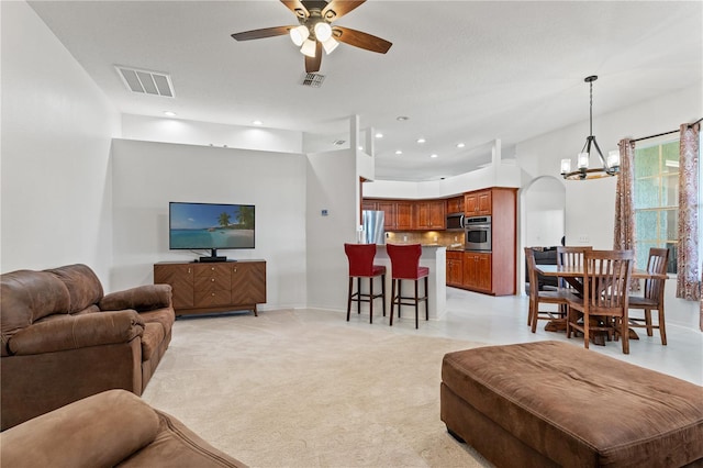 living room featuring light carpet, visible vents, ceiling fan with notable chandelier, and recessed lighting