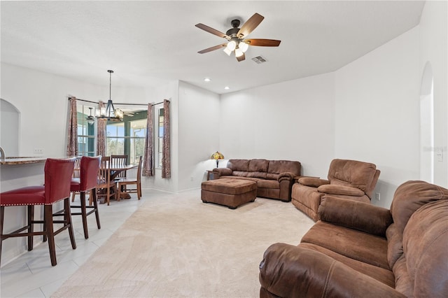 living room with visible vents, light carpet, ceiling fan with notable chandelier, arched walkways, and light tile patterned floors