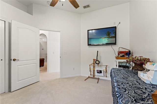 sitting room featuring visible vents, arched walkways, baseboards, light colored carpet, and ceiling fan