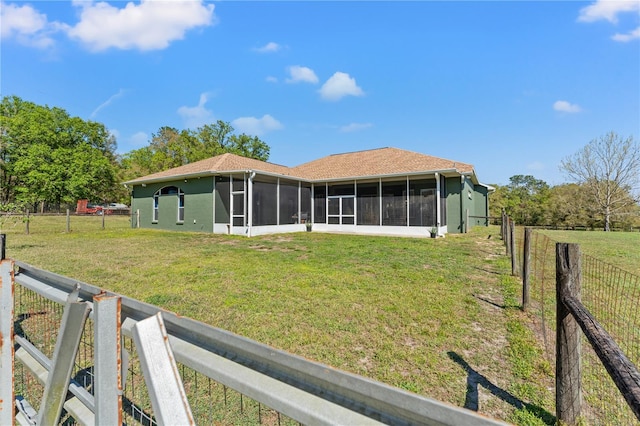 back of property featuring stucco siding, a lawn, a fenced backyard, and a sunroom