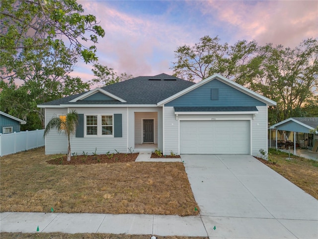 ranch-style home featuring a garage, fence, driveway, a yard, and roof with shingles