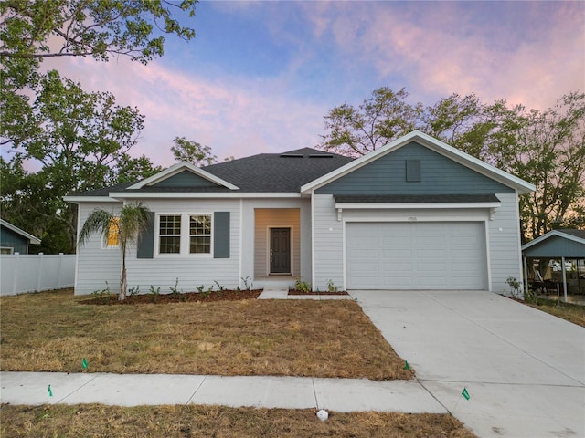 ranch-style house with a shingled roof, concrete driveway, a lawn, fence, and a garage