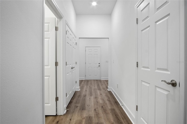 corridor with light wood-style flooring and baseboards