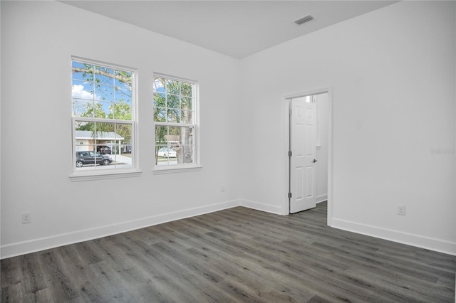 empty room with visible vents, dark wood finished floors, and baseboards