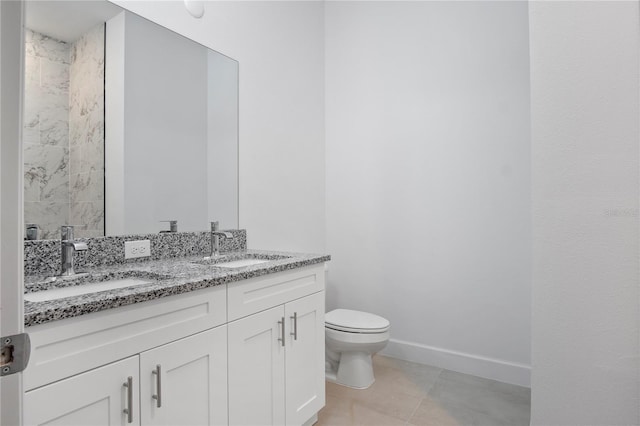 bathroom featuring toilet, a sink, baseboards, and double vanity