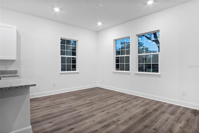 unfurnished dining area featuring baseboards, dark wood-type flooring, and recessed lighting