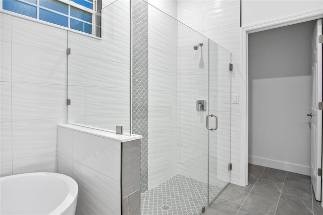 bathroom with a soaking tub, a shower stall, and baseboards