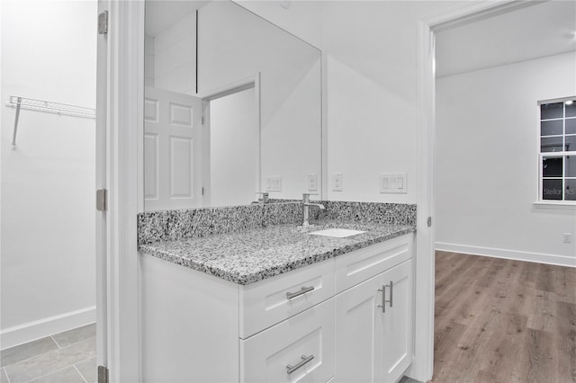 interior space with wood finished floors, a walk in closet, vanity, and baseboards