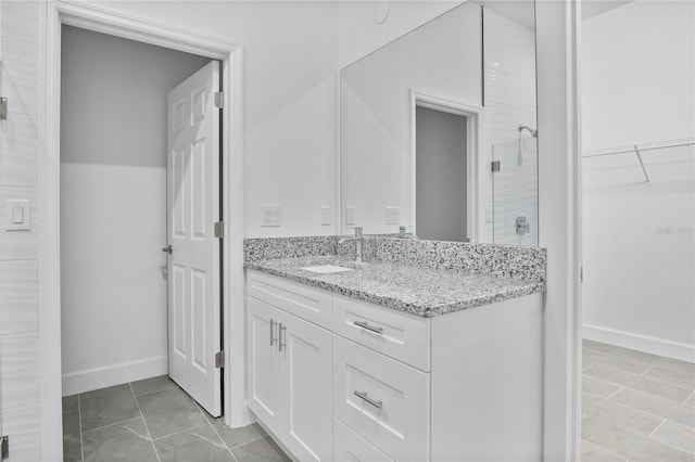 full bathroom featuring a walk in closet, baseboards, a shower stall, and vanity