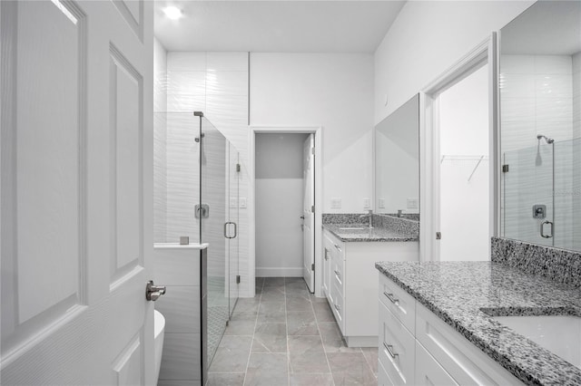 full bathroom featuring a stall shower, two vanities, a walk in closet, and a sink