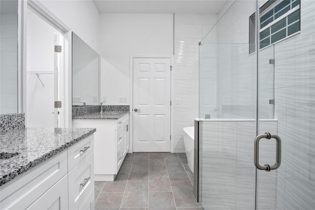 full bath featuring a stall shower, a walk in closet, and vanity