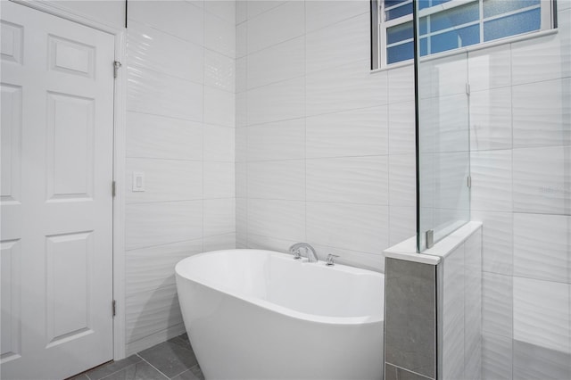 full bath featuring a soaking tub, a tile shower, and tile walls