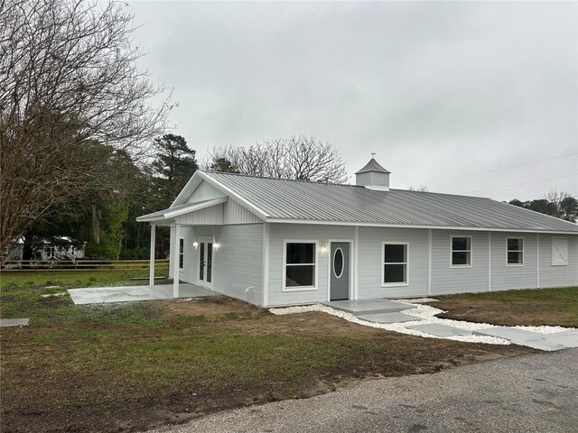 view of front of home featuring a front yard, a patio, and metal roof