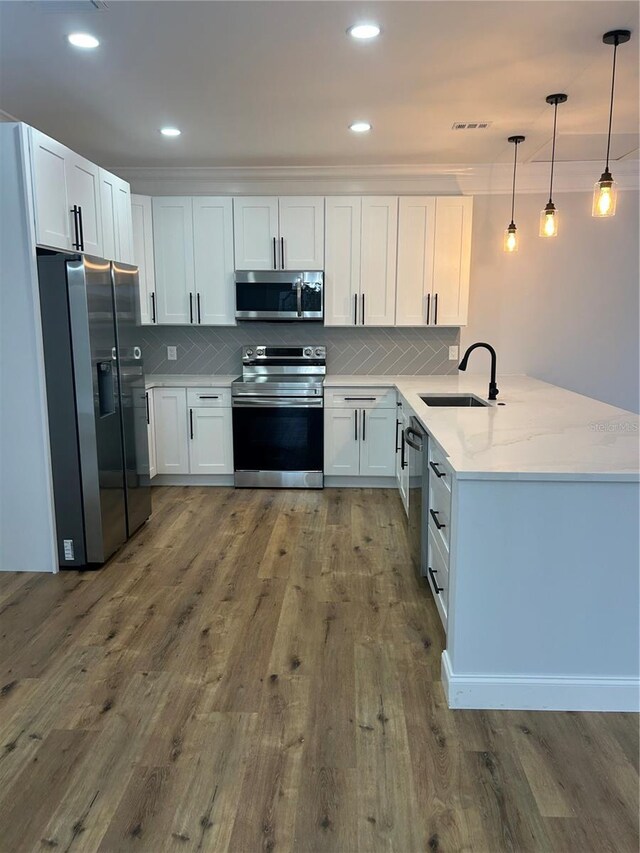 kitchen with stainless steel appliances, backsplash, a sink, dark wood-type flooring, and a peninsula