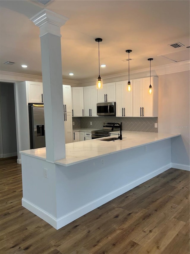 kitchen featuring white cabinets, stainless steel appliances, a peninsula, backsplash, and ornamental molding