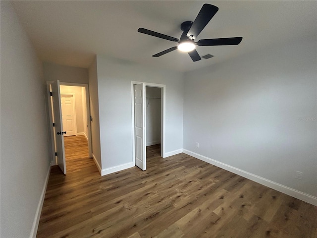 unfurnished bedroom featuring wood finished floors, baseboards, a closet, and a ceiling fan