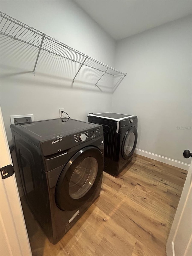 laundry room featuring washing machine and clothes dryer, baseboards, light wood finished floors, and laundry area