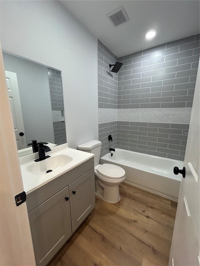 full bathroom with toilet, visible vents, shower / washtub combination, wood finished floors, and vanity