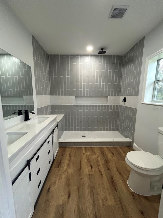 bathroom with toilet, wood finished floors, a sink, and visible vents