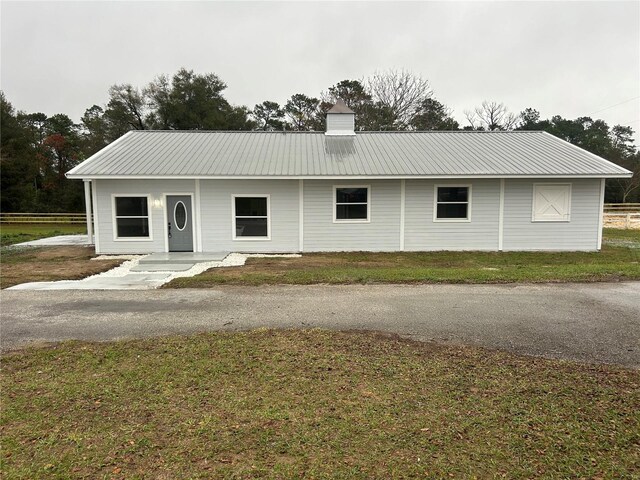 view of front of property featuring a front lawn, a chimney, and metal roof