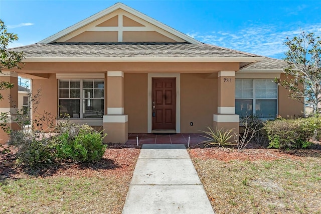 bungalow-style house featuring covered porch, roof with shingles, and stucco siding