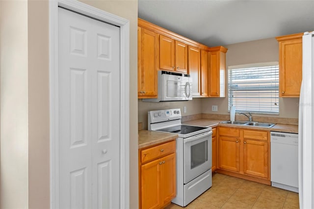 kitchen featuring white appliances, light tile patterned floors, light countertops, and a sink