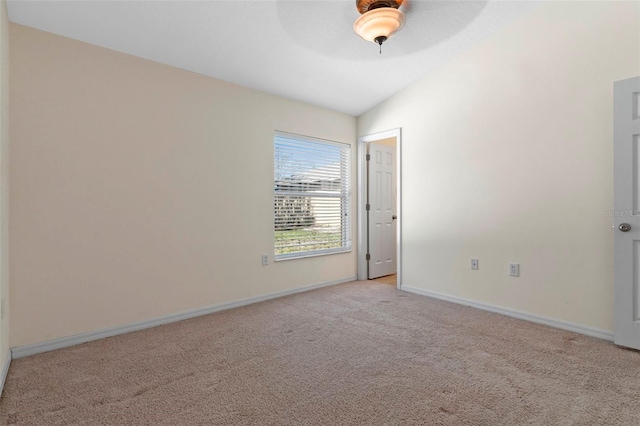 spare room with light colored carpet, vaulted ceiling, baseboards, and ceiling fan