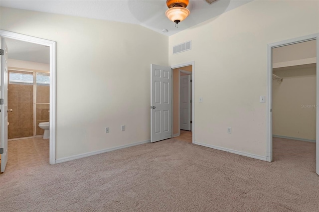 unfurnished bedroom featuring visible vents, baseboards, carpet, a spacious closet, and vaulted ceiling