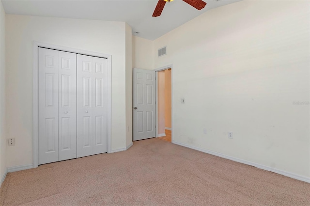 unfurnished bedroom featuring baseboards, visible vents, light colored carpet, lofted ceiling, and a closet