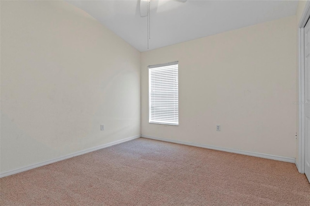 unfurnished room featuring vaulted ceiling, baseboards, and light colored carpet