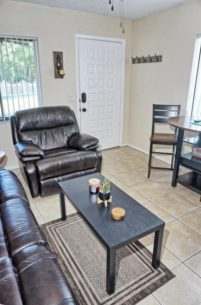 living room featuring a textured ceiling, light tile patterned flooring, and baseboards