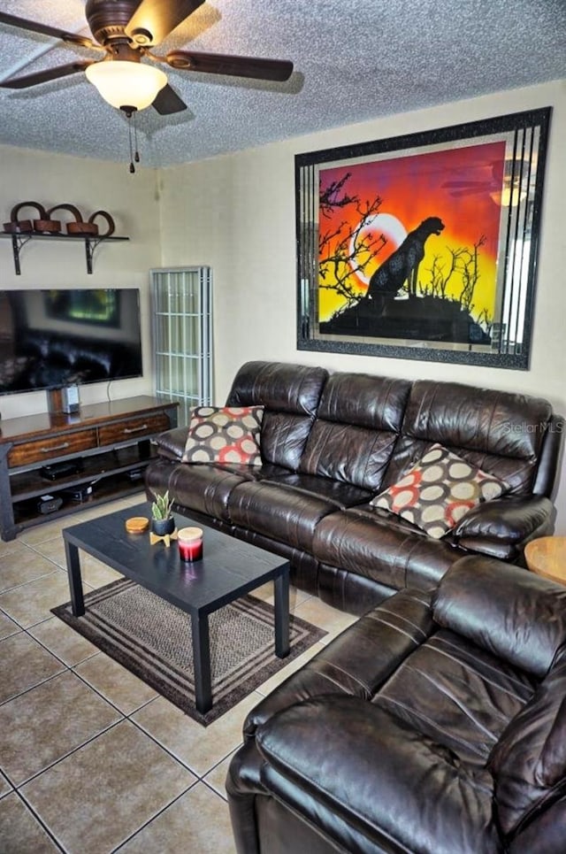 living room featuring tile patterned flooring, a ceiling fan, and a textured ceiling