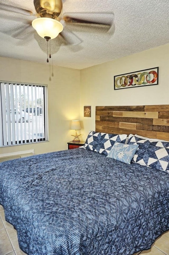 bedroom featuring light tile patterned floors, ceiling fan, and a textured ceiling