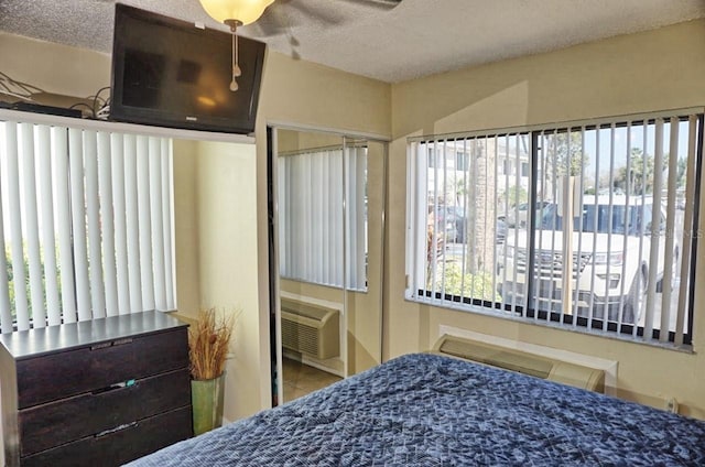 tiled bedroom featuring a textured ceiling, multiple windows, and a wall unit AC