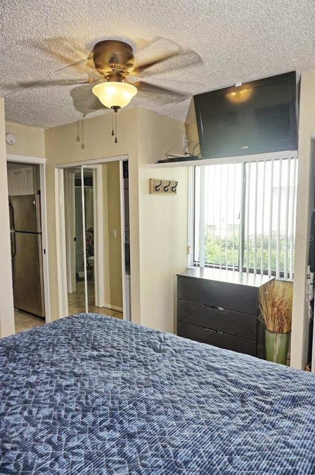 bedroom with a textured ceiling, freestanding refrigerator, and a ceiling fan