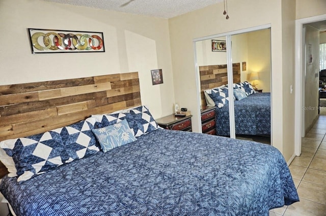 bedroom with a closet, a textured ceiling, and light tile patterned flooring