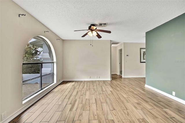 unfurnished room with light wood-type flooring, ceiling fan, visible vents, and a textured ceiling