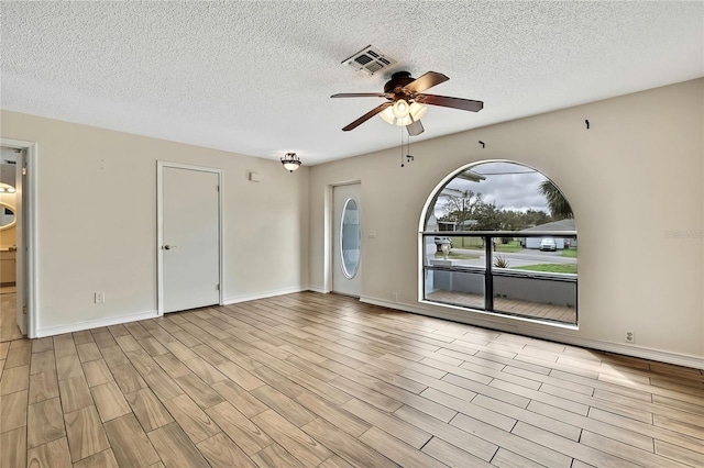 unfurnished room with a ceiling fan, light wood-type flooring, visible vents, and baseboards