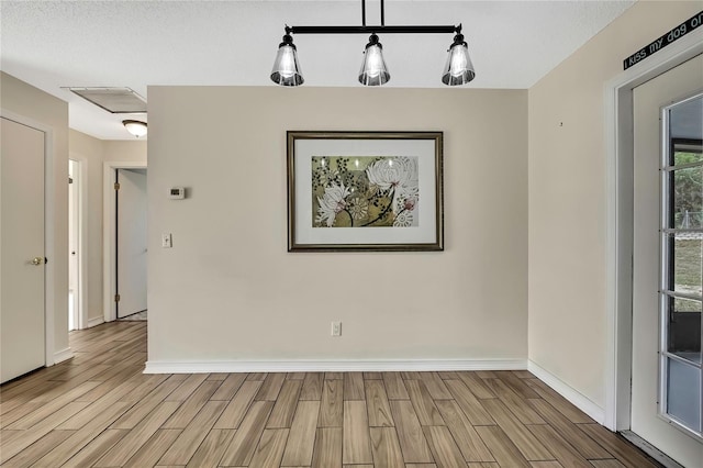 empty room with wood finish floors, visible vents, and baseboards