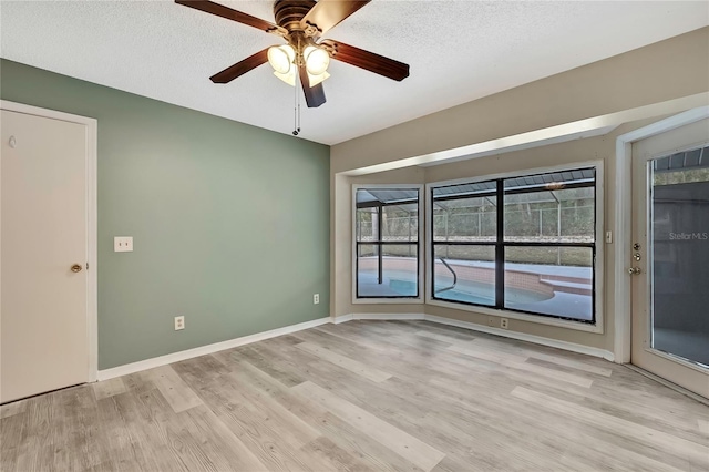 spare room featuring light wood-style floors, ceiling fan, a textured ceiling, and baseboards