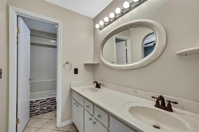 full bathroom with tile patterned flooring, a sink, a textured ceiling, and double vanity