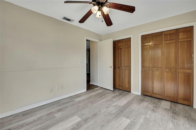 unfurnished bedroom featuring ceiling fan, visible vents, baseboards, multiple closets, and light wood finished floors