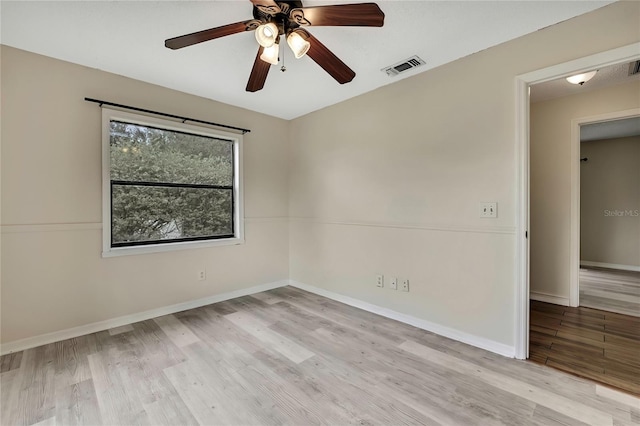 unfurnished room with baseboards, a ceiling fan, visible vents, and light wood-style floors