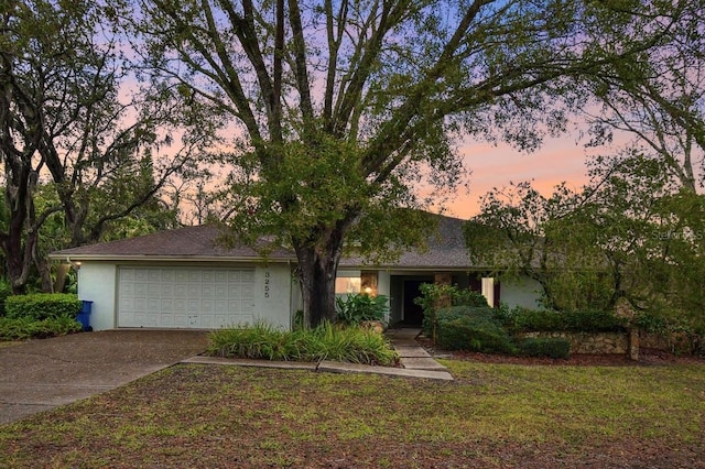 view of front of property featuring concrete driveway, a yard, an attached garage, and stucco siding