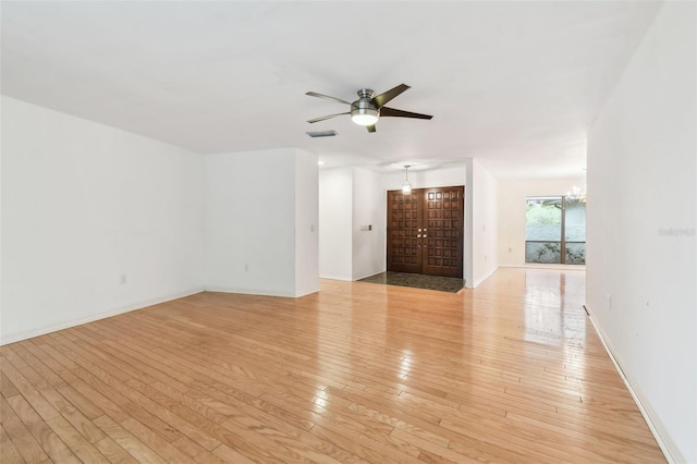 unfurnished living room with light wood finished floors, baseboards, visible vents, and ceiling fan with notable chandelier