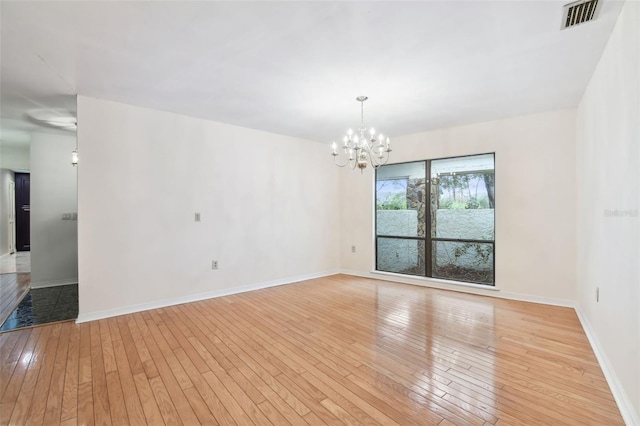 spare room with light wood-style floors, baseboards, visible vents, and ceiling fan with notable chandelier